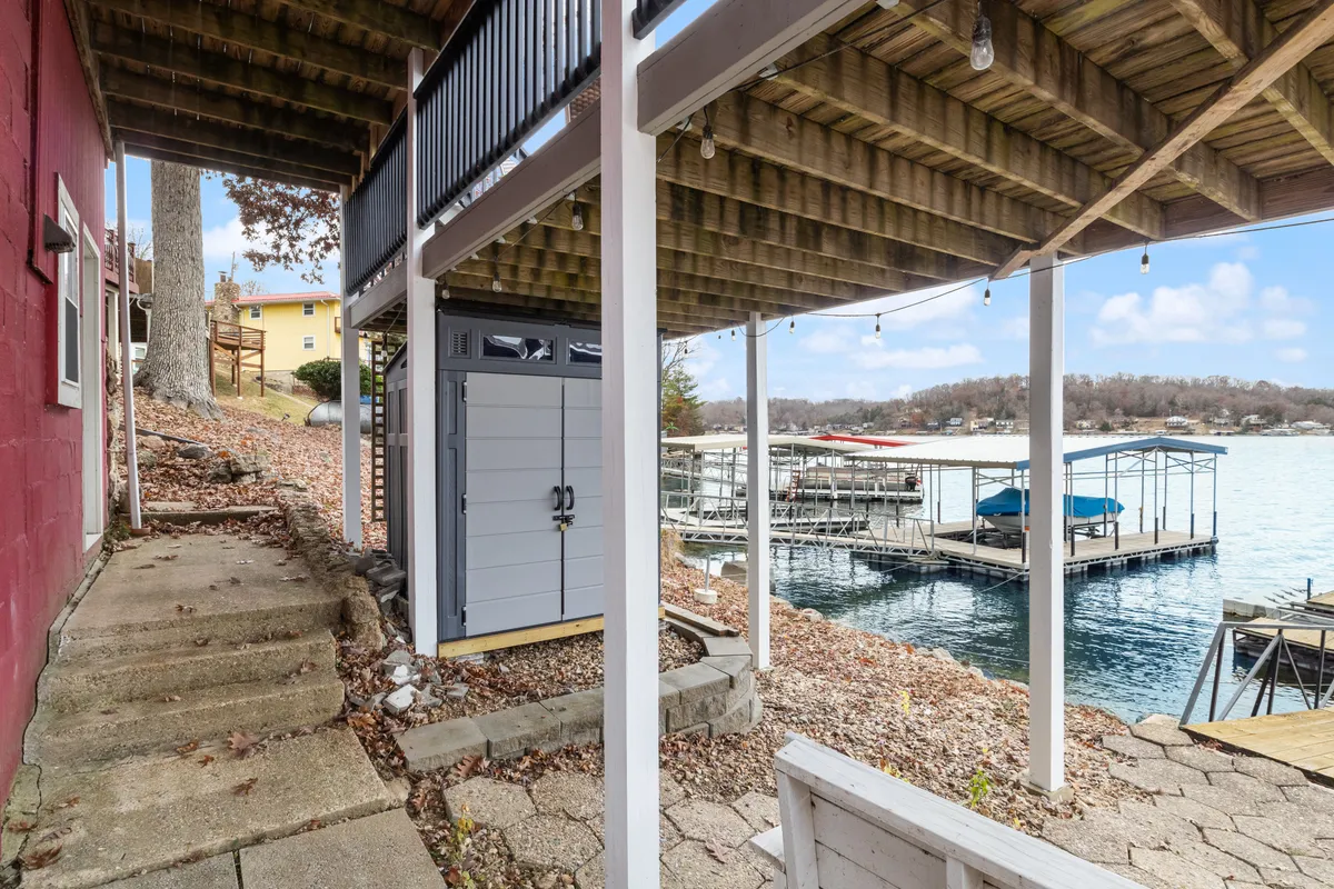 A serene exterior image featuring a waterfront view, dock, outdoor stairs, and a storage shed. It evokes the spirit of lakeside living with spaces ready for boating, fishing, and easy access from the property to the water.
