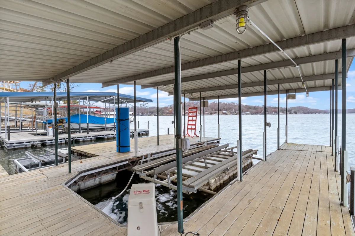 A tranquil scene featuring a private dock extending over calm lake waters, with a boathouse in the distance. The golden hour light suggests the serenity of sunset, perfect for quiet moments together by the water.