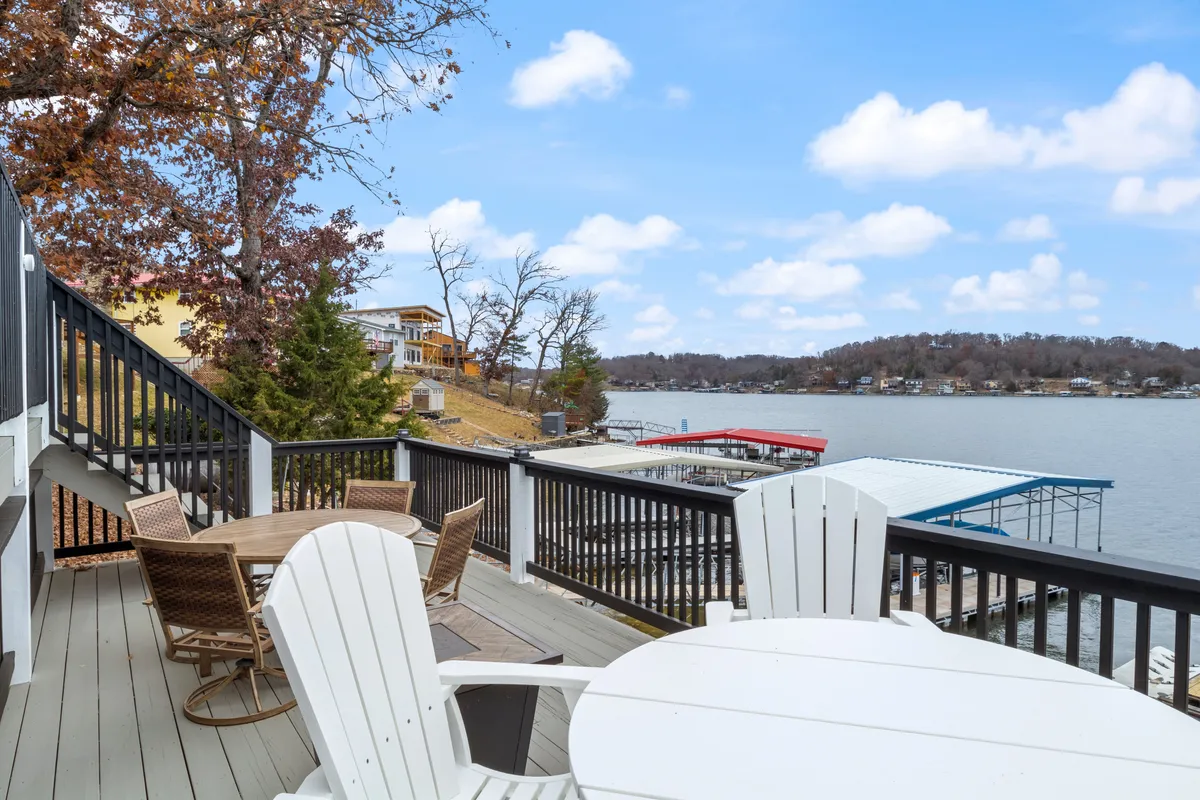 An exterior shot that highlights comfortable deck furniture with views over the lake and visible docks. The scene conveys the proximity to the water, the inviting outdoor relaxation spaces, and the effortless transition from the property to aquatic activities.