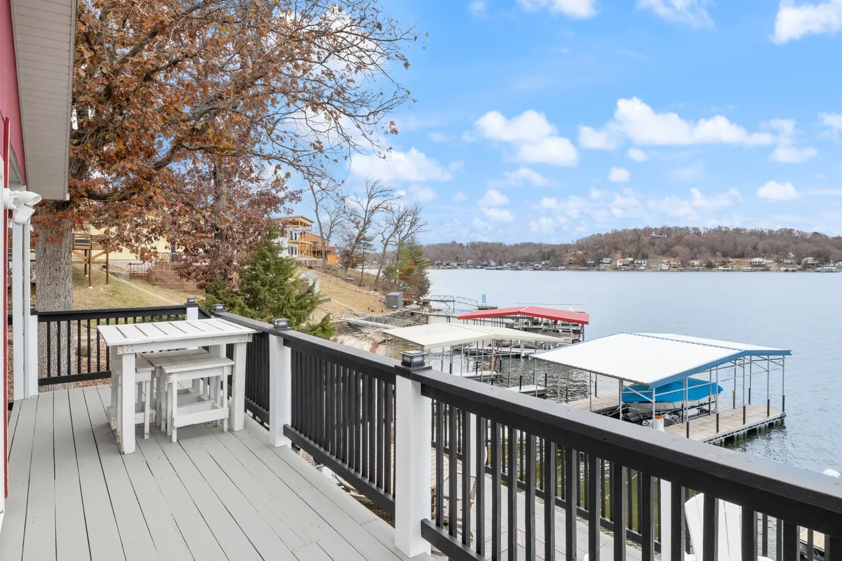 A serene exterior dining area with a table set for outdoor meals, overlooking the lake and surrounded by boathouses and tranquil water. The space is perfect for hosting family meals or sunset gatherings after a day on the water.