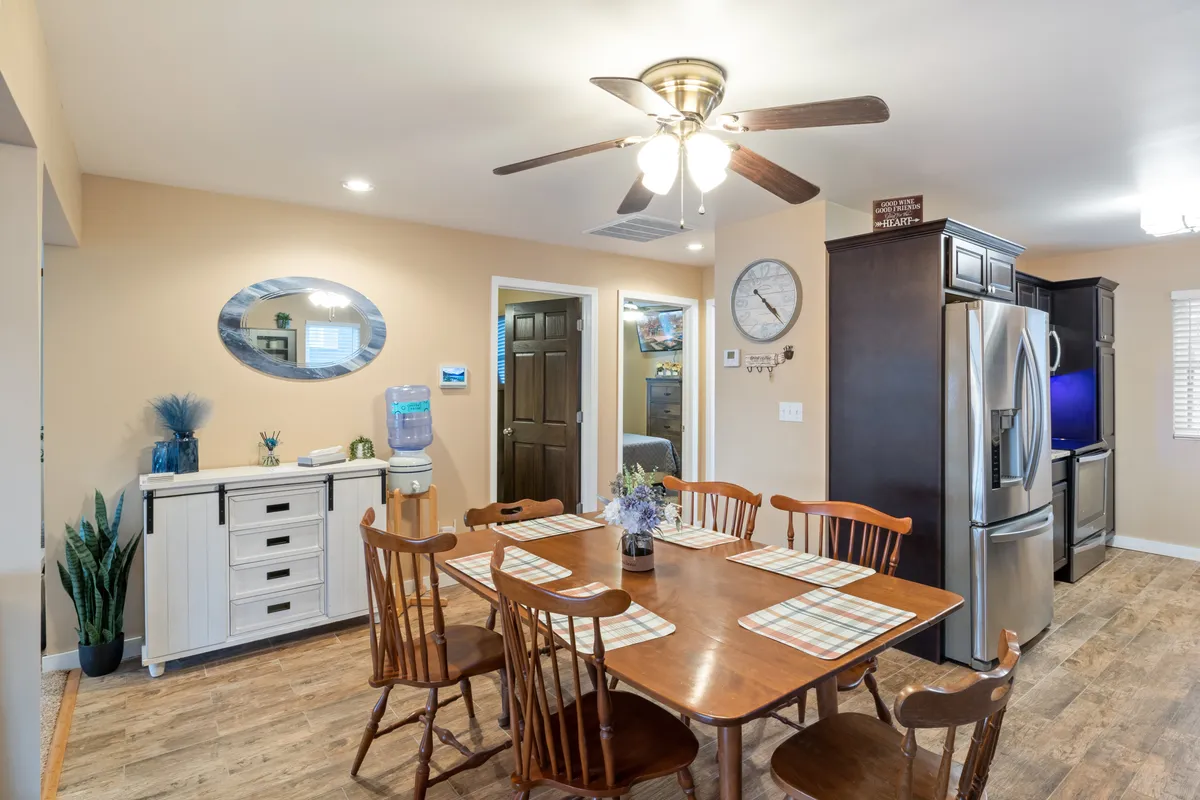 A welcoming dining area situated next to the kitchen, featuring a dining table, modern appliances, a decorative mirror, and a water cooler. The space is styled for shared meals and casual gatherings.